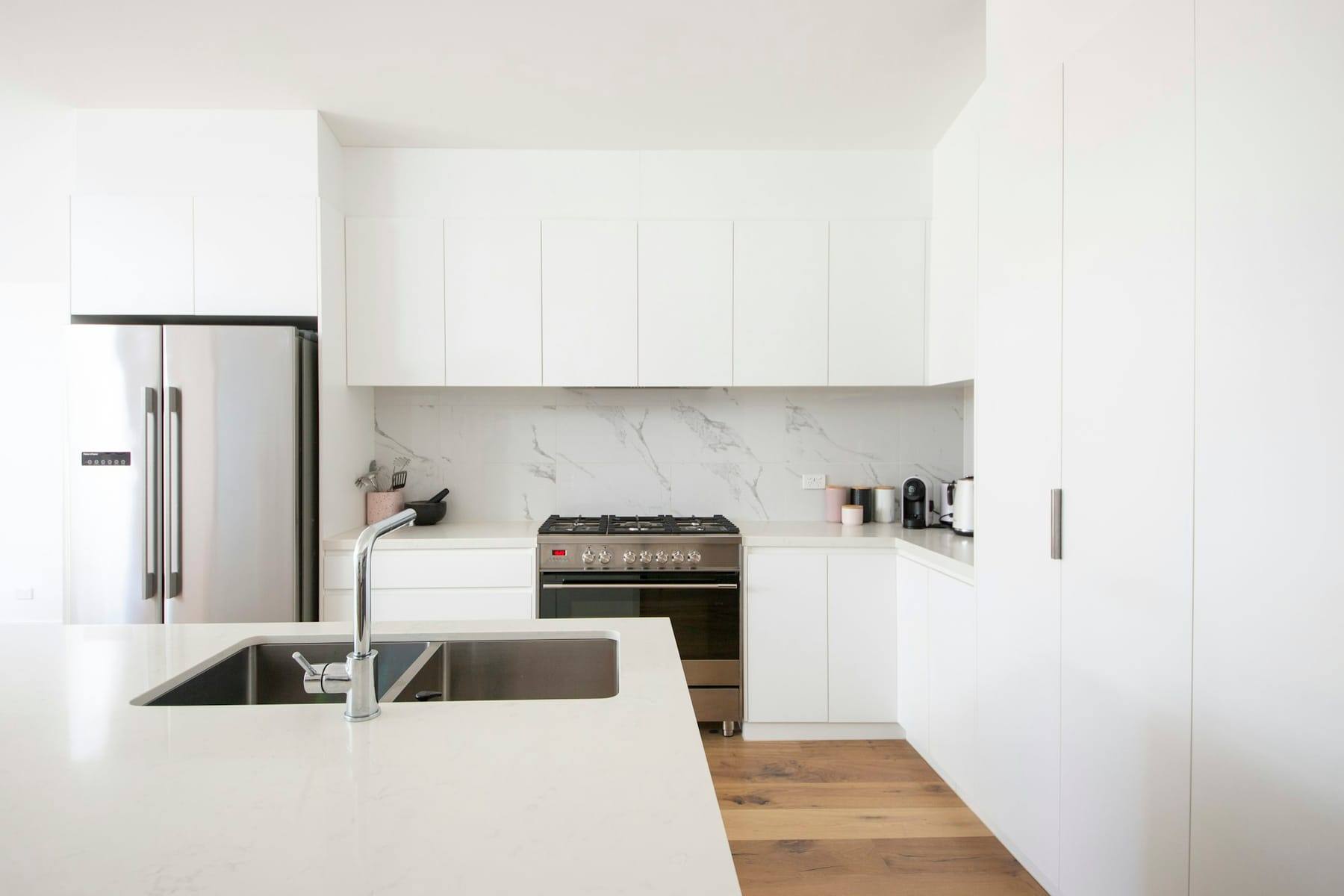 Bright white kitchen with a marble backsplash and wooden floor